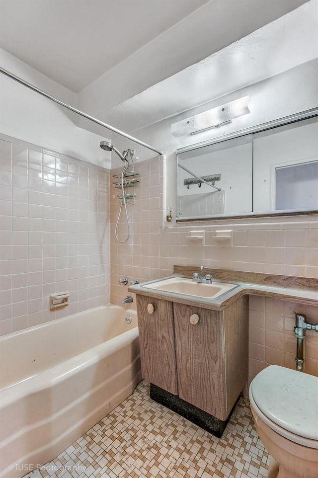 full bathroom featuring tile walls, vanity, tiled shower / bath combo, and toilet