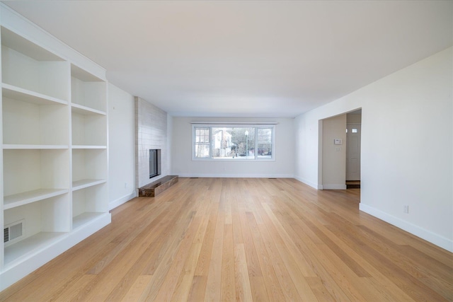 unfurnished living room featuring built in features, a fireplace, and light hardwood / wood-style floors