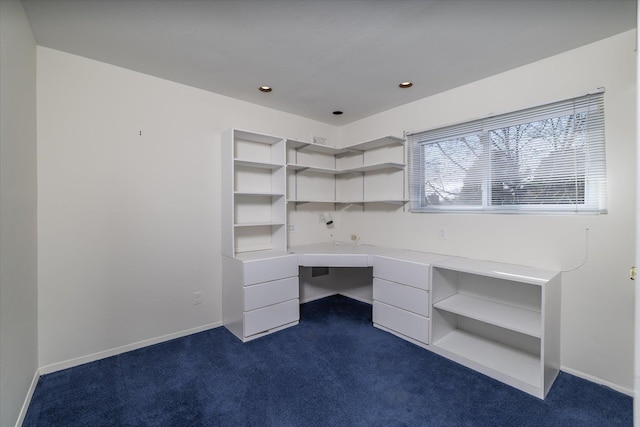 unfurnished office with dark colored carpet and built in desk