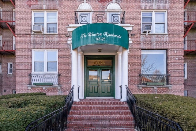 doorway to property featuring fence and brick siding