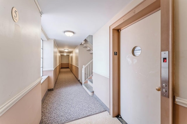 corridor with elevator and carpet