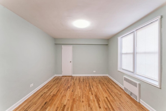 empty room featuring radiator heating unit and light hardwood / wood-style floors