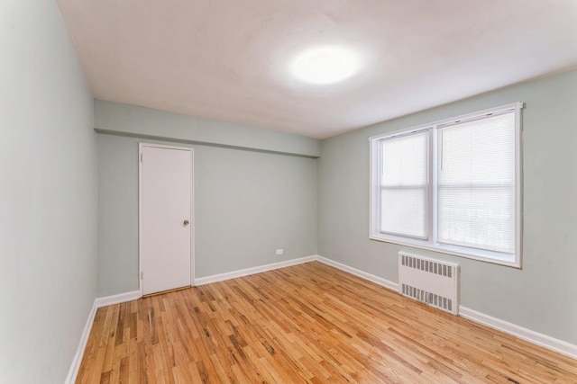 empty room with radiator heating unit and light wood-type flooring