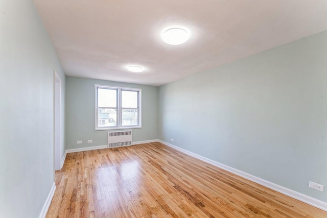 spare room featuring radiator heating unit and light hardwood / wood-style floors