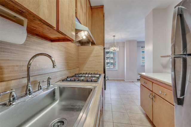 kitchen with sink, light tile patterned floors, appliances with stainless steel finishes, hanging light fixtures, and backsplash