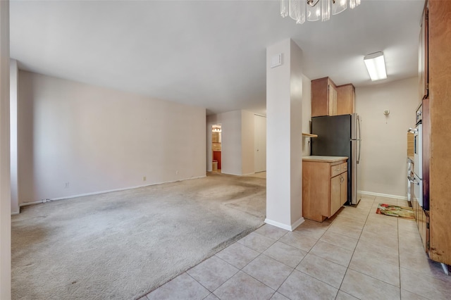 kitchen with pendant lighting, light colored carpet, stainless steel fridge, and a chandelier