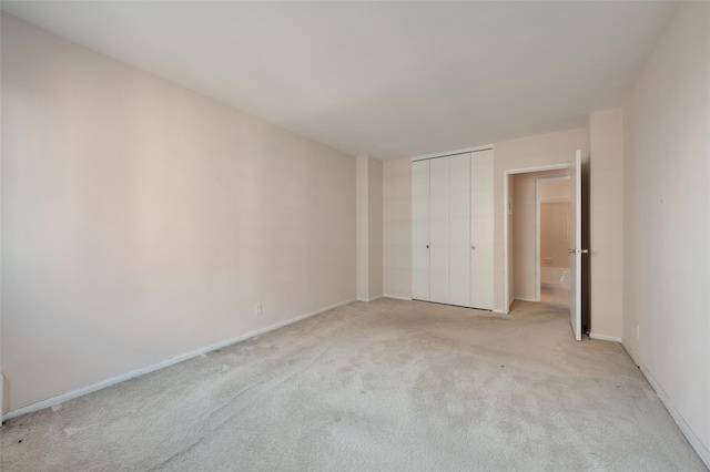 unfurnished bedroom featuring light colored carpet and a closet