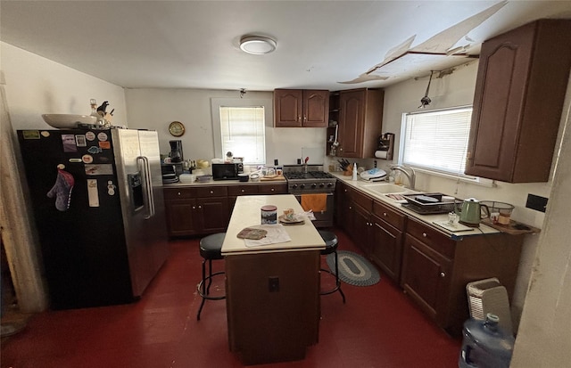 kitchen with sink, a center island, a kitchen breakfast bar, a wealth of natural light, and stainless steel appliances