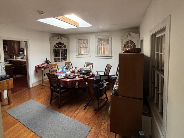 dining room with wood-type flooring and a skylight