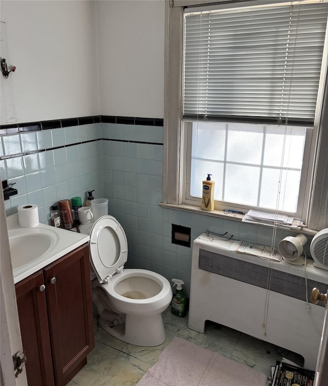 bathroom featuring vanity, radiator heating unit, tile walls, and toilet
