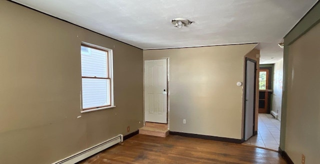 spare room with wood-type flooring and a baseboard heating unit