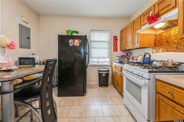 kitchen featuring sink, light tile patterned floors, electric panel, gas range gas stove, and black fridge