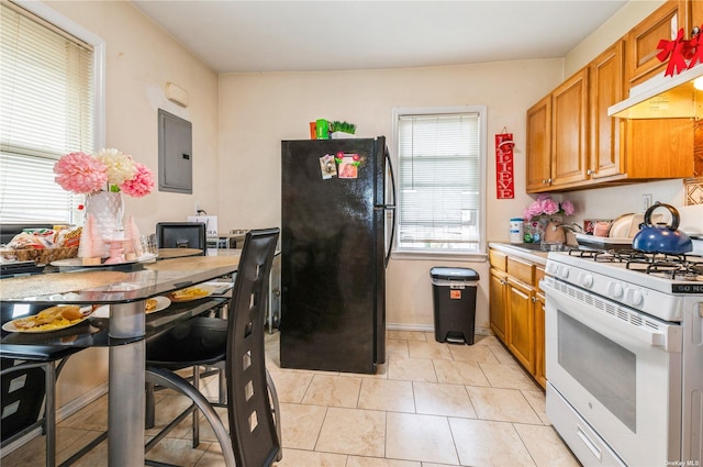 kitchen featuring sink, light tile patterned floors, electric panel, white gas range oven, and black fridge