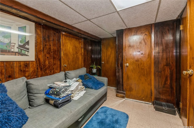 interior space with a drop ceiling and wood walls