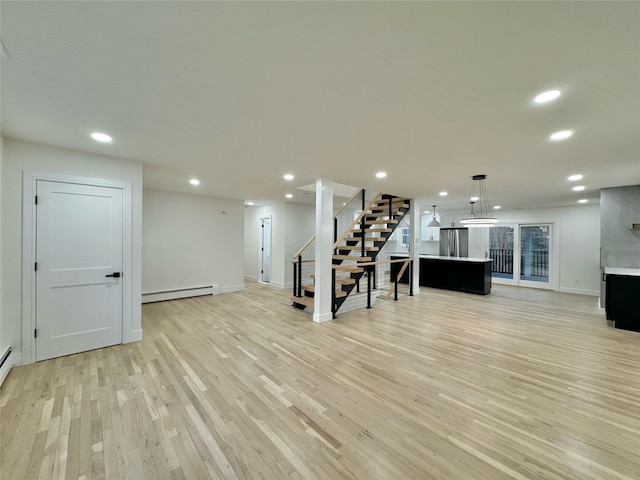 basement featuring baseboard heating, stainless steel fridge, and light hardwood / wood-style flooring