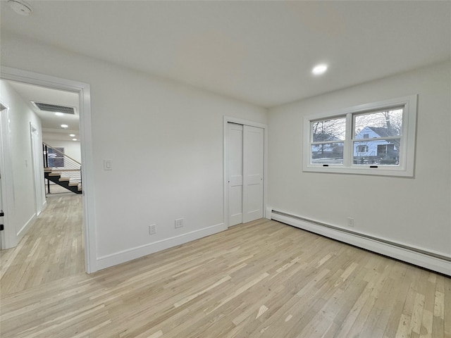 unfurnished bedroom with a baseboard radiator, light wood-type flooring, and a closet