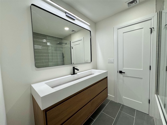 bathroom featuring tiled shower, vanity, and tile patterned flooring