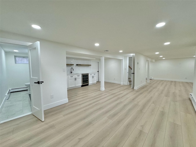 basement featuring light hardwood / wood-style flooring, wet bar, beverage cooler, and a baseboard radiator