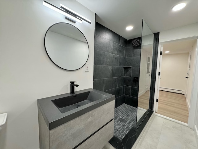 bathroom featuring vanity, tiled shower, and baseboard heating