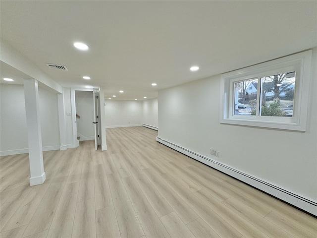 basement with baseboard heating and light hardwood / wood-style flooring