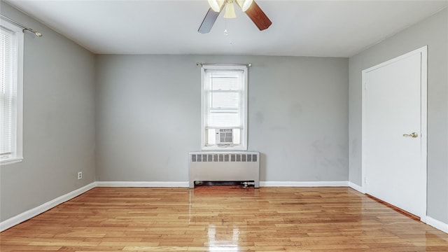 empty room featuring ceiling fan, radiator heating unit, and light hardwood / wood-style flooring