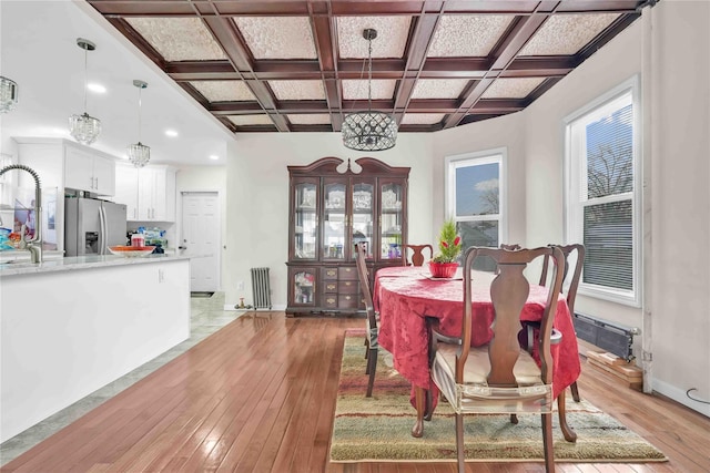 dining room featuring beamed ceiling, coffered ceiling, sink, and light hardwood / wood-style floors