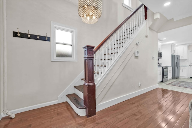 stairs featuring hardwood / wood-style floors, a high ceiling, and a notable chandelier