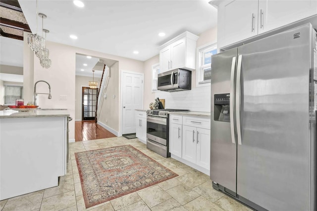 kitchen featuring white cabinetry, appliances with stainless steel finishes, pendant lighting, and backsplash