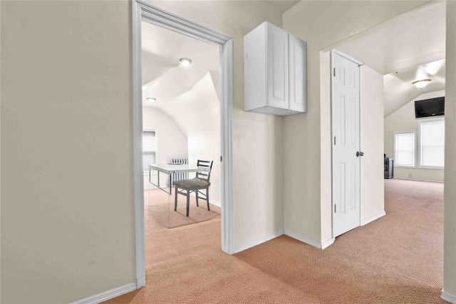 hall featuring light colored carpet and vaulted ceiling