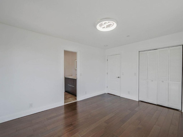 unfurnished bedroom with connected bathroom, a closet, and dark hardwood / wood-style floors