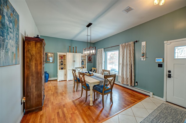 dining area with light tile patterned flooring, plenty of natural light, a notable chandelier, and baseboard heating