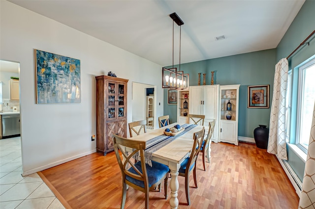 dining room with a notable chandelier, a baseboard radiator, and light wood-type flooring