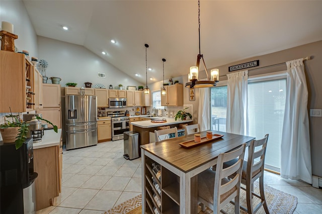 kitchen with light brown cabinetry, decorative light fixtures, light tile patterned floors, a kitchen island, and stainless steel appliances