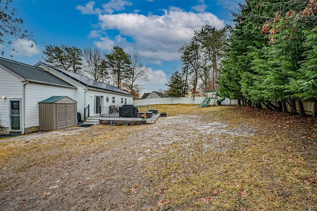 view of yard featuring a wooden deck, a storage shed, and a playground