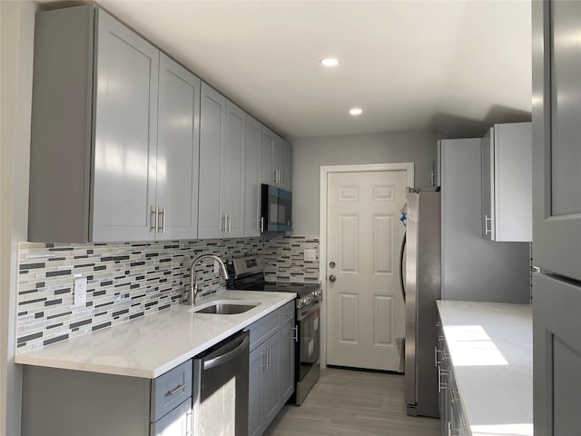 kitchen with stainless steel appliances, sink, gray cabinetry, and backsplash