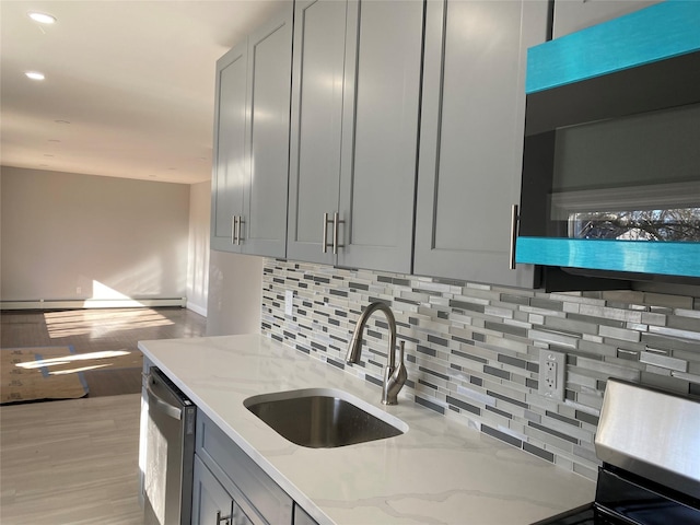 kitchen featuring sink, gray cabinetry, light stone counters, stainless steel dishwasher, and backsplash