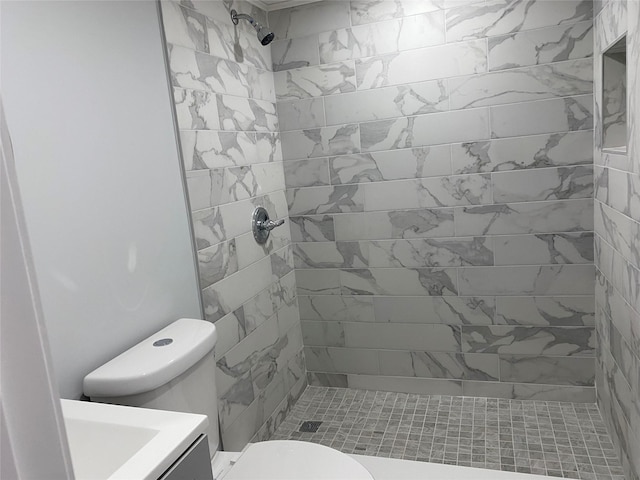 bathroom featuring vanity, a tile shower, and toilet