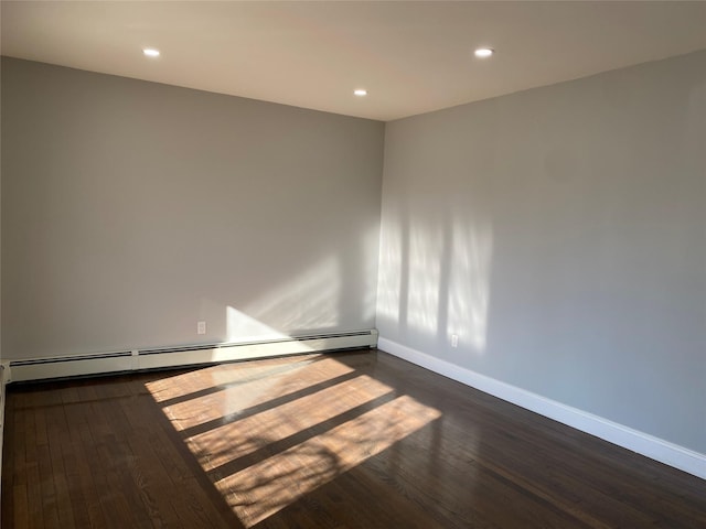 spare room with a baseboard heating unit and dark hardwood / wood-style floors