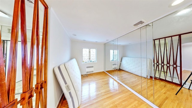 foyer with hardwood / wood-style flooring, crown molding, and radiator