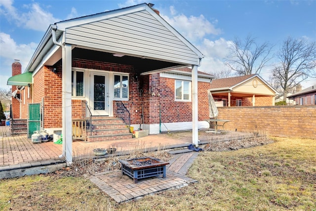 rear view of property featuring a patio area and an outdoor fire pit