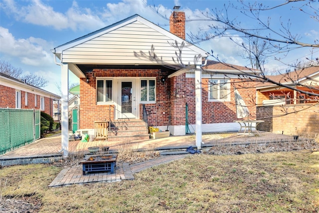 back of house with a lawn, a patio area, and a fire pit