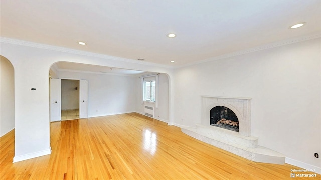 unfurnished living room featuring hardwood / wood-style flooring, crown molding, and a high end fireplace