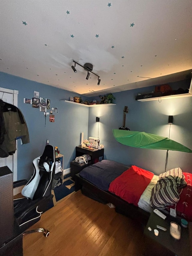 bedroom with hardwood / wood-style flooring and track lighting