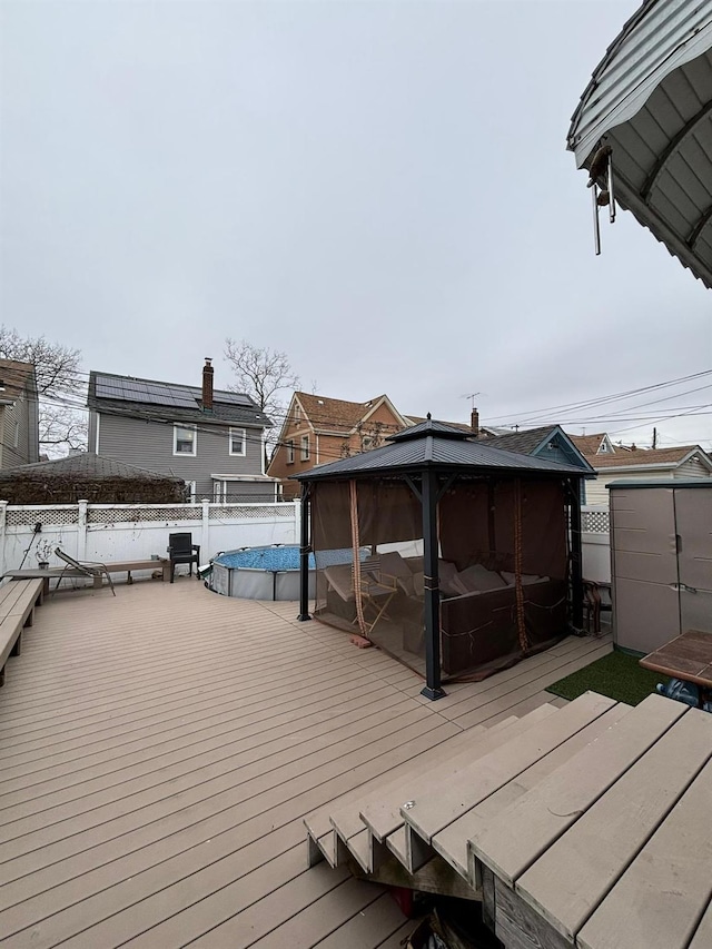 wooden terrace with a gazebo and a covered pool