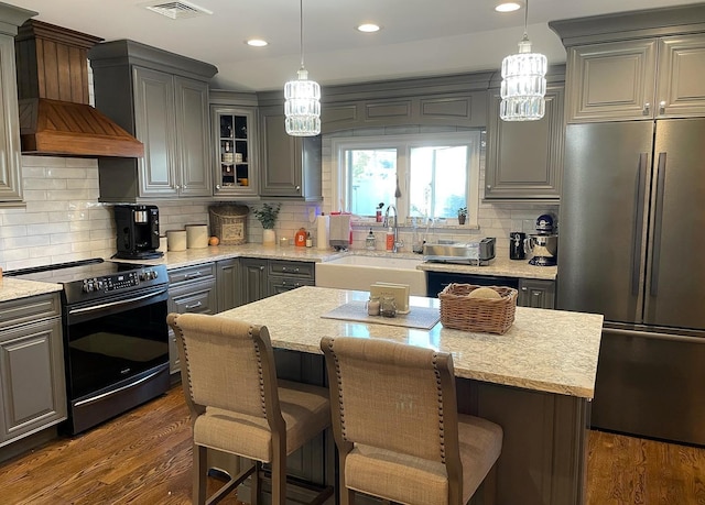 kitchen with a kitchen island, sink, gray cabinetry, stainless steel appliances, and custom range hood