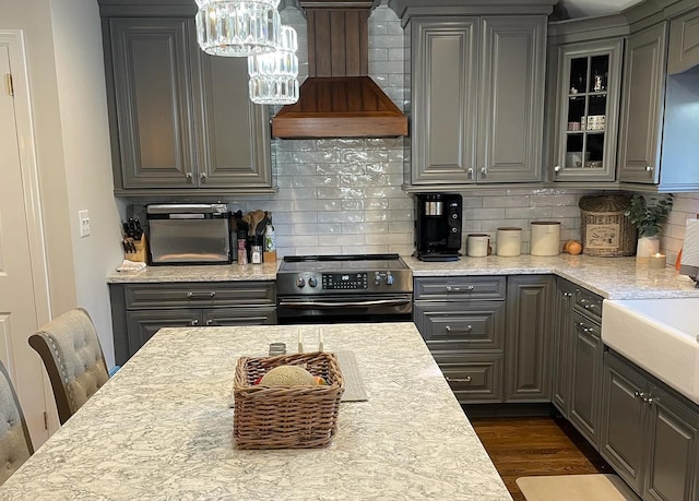 kitchen with gray cabinets, backsplash, dark hardwood / wood-style flooring, black range with electric cooktop, and custom exhaust hood