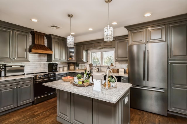 kitchen featuring appliances with stainless steel finishes, dark hardwood / wood-style flooring, a center island, light stone counters, and custom range hood