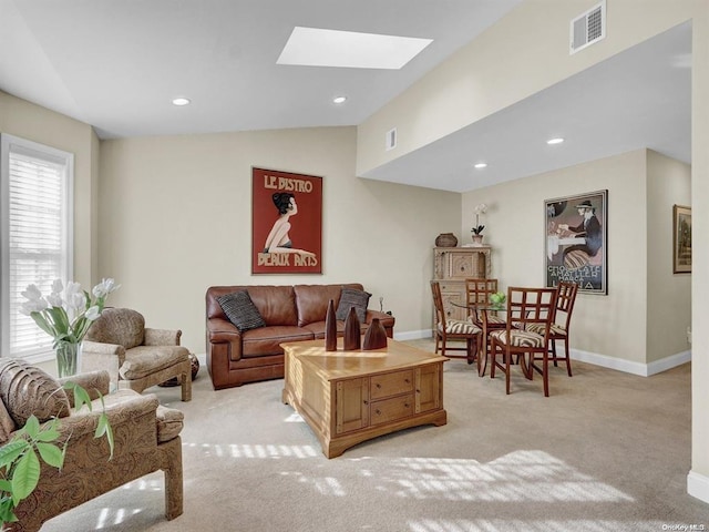 living room featuring lofted ceiling with skylight and light carpet