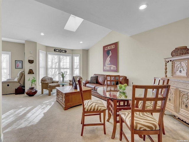 dining room featuring light carpet and lofted ceiling with skylight