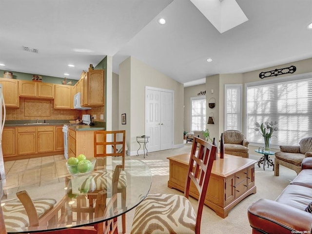 living room with light carpet, sink, and vaulted ceiling with skylight